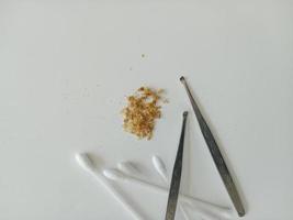 Closeup of Earwax and two ear pick tools and cotton swabs On the light blue table top photo