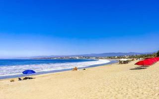 Puerto Escondido Oaxaca Mexico 2023 People parasols sun loungers beach waves palms Zicatela Mexico. photo