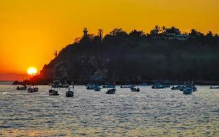 Colorful golden sunset boats wave and beach Puerto Escondido Mexico. photo