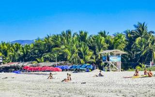 Puerto Escondido Oaxaca Mexico 2023 People parasols sun loungers beach waves palms Zicatela Mexico. photo