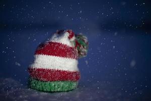 de punto Navidad sombrero en un azul Nevado antecedentes. gracioso Navidad sombrero en nieve antecedentes. foto