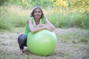 mayor hermosa mujer es haciendo yoga con un pelota en naturaleza. foto