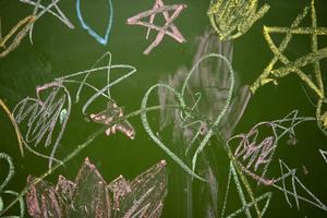 dibujos de niños con tiza en un colegio verde tablero. foto