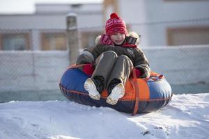 A happy boy up in the air on a tube sledding in the snow.. A boy slides down a hill in winter. photo