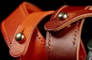 Part of a leather product or belt with a metal rivet on a black background. photo