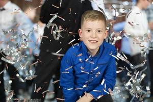 contento pequeño chico en confeti.magia hora - retrato de un muy contento niño con manos sonriente mientras que cae papel picado. a un para niños fiesta. foto