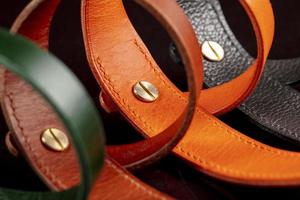 A group of multi-colored leather belts on a black background. photo