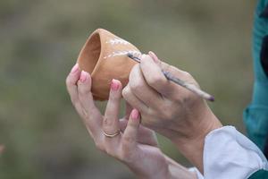 pintar con un cepillo en un arcilla bol. artesanía y vajilla haciendo. foto