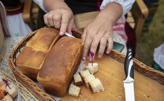un pan saboreo. manos cortar muestras de un pan para pruebas. foto