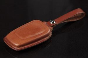 Leather case for car keys on a black background. photo