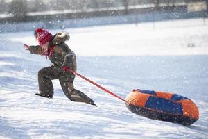 A happy boy up in the air on a tube sledding in the snow.. A boy slides down a hill in winter. photo