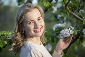 hermosa mujer en un floreciente jardín, sonriente, disfrutando vida foto