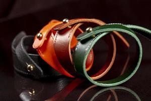 A group of multi-colored leather belts on a black background. photo