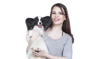 un linda joven mujer es abrazando su Papillon cachorro. amor Entre propietario y perro. niña con perro estudio retrato. foto