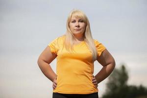 retrato de una mujer europea de mediana edad en chándal, posando para la cámara, relajándose. emocionada mujer con sobrepeso en chándal de moda descansando después de hacer ejercicio. foto