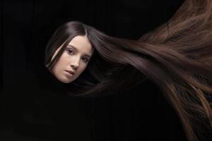 Long dark hair. The face of a girl with flowing hair on a dark background. photo