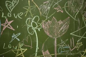 Drawings of children with chalk on a school green board. photo