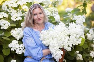 Beautiful elderly woman with a bouquet of flowers. Smiling woman in her garden. photo