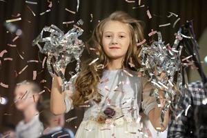 Happy face of a little girl in falling confetti. Magic Time - Portrait of a very happy child with hands smiling while confetti falls. For a children's party or birthday. photo