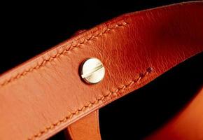 Part of a leather belt on a dark background. photo