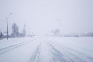 Snow covered foggy road in bad winter weather. photo