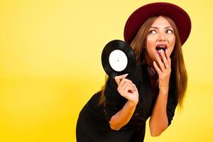 girl in a black suit on a yellow background with a record in her hands, music, the girl shows emotions photo