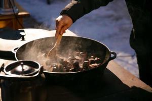 open-air kitchen, frying homemade sausages in sauce photo