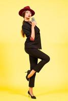 girl in a black suit on a yellow background sings in a retro microphone, portrait, music, full growth photo