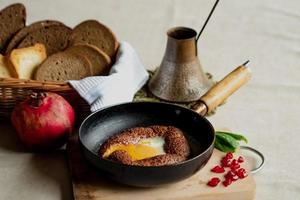 Turkish breakfast, scrambled eggs in a simit bun in a frying pan, coffee in a Turk, fresh bread photo