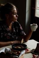 Girl having breakfast in the kitchen early in the morning photo