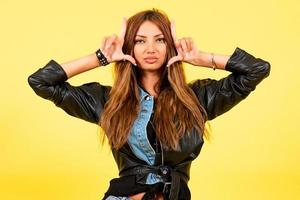 Yellow background, a girl in a leather jacket with a rock style, shows emotions photo