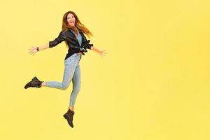 Yellow background, a girl in a leather jacket in the style of rock, shows emotions, free space for text, jumps photo