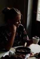 Girl having breakfast in the kitchen early in the morning photo