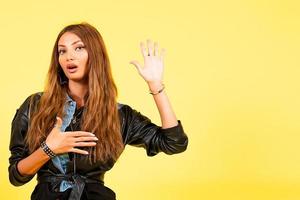 Yellow background, a girl in a leather jacket in the style of rock, shows emotions, free space for text, swears photo