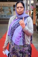 New Delhi, India - December 04 2022 - Unidentified people showing their ink-marked fingers after casting votes in front of polling booth of east Delhi area for MCD local body Elections 2022 photo