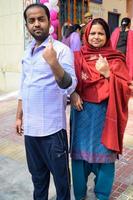 New Delhi, India - December 04 2022 - Unidentified people showing their ink-marked fingers after casting votes in front of polling booth of east Delhi area for MCD local body Elections 2022 photo