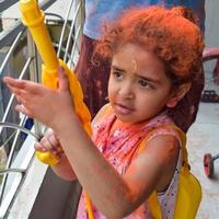 Sweet little Indian girl playing colours on Holi festival, holding pichakaree full of colours, Holi festival celebrations in Delhi, India photo