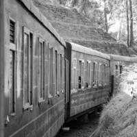 Toy Train moving on mountain slope, beautiful view, 1 side mountain, 1 side valley moving on railway to the hill, among green natural forest. Toy train from Kalka to Shimla in India-Black and White photo