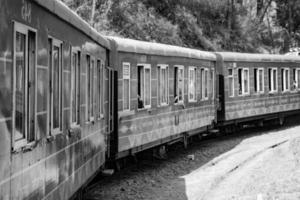 Toy Train moving on mountain slope, beautiful view, 1 side mountain, 1 side valley moving on railway to the hill, among green natural forest. Toy train from Kalka to Shimla in India-Black and White photo