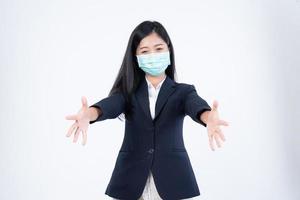 A confident beautiful young Asian business woman wearing green medical face mask and black suit, standing with her arms folded and looking at camera isolated on white background. photo