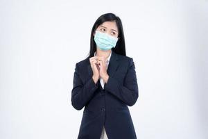 un confidente hermosa joven asiático negocio mujer vistiendo verde médico cara máscara y negro traje, en pie con su brazos doblada y mirando a cámara aislado en blanco antecedentes. foto