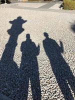 Shadow of two men holding up two fingers next to a stone lantern in Kamakura, Japan photo