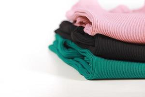 Pile of knitted warm colorfull sweaters with different knitting patterns folded in stack on white background, white wall background. Fall winter season knitwear. Close up, copy space for text photo