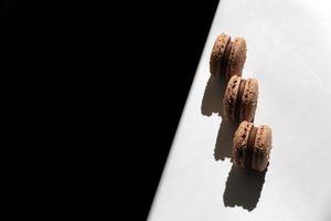 Sweet brown chocolate french macaroons or macarons dessert isolated on white background with light rays from window. copy space. photo