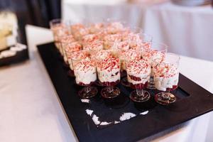 nimiedad rojo terciopelo con crema queso crema y Cereza geles en vaso taza. dulce hecho en casa parfait postre con azotado crema. caramelo bar en cumpleaños fiesta, boda. foto