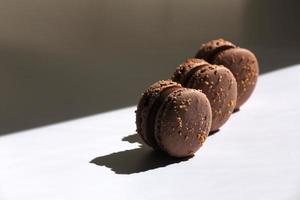 Sweet brown chocolate french macaroons or macarons dessert isolated on white background with light rays from window. copy space. photo