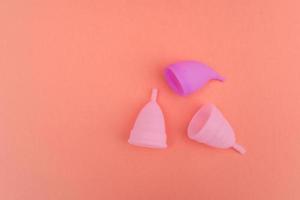 different tips of medical silicone menstrual period female cups isolated on peach background, reusable ecologic, zero waste concept photo