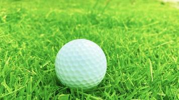 Golf ball close up on green grass on blurred beautiful landscape of golf course with sunrise,sunset time on background.Concept international sport that rely on precision skills for health relaxation. photo