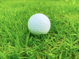 Golf ball close up on green grass on blurred beautiful landscape of golf course with sunrise,sunset time on background.Concept international sport that rely on precision skills for health relaxation. photo