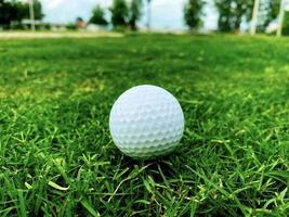 Golf ball close up on green grass on blurred beautiful landscape of golf course with sunrise,sunset time on background.Concept international sport that rely on precision skills for health relaxation. photo